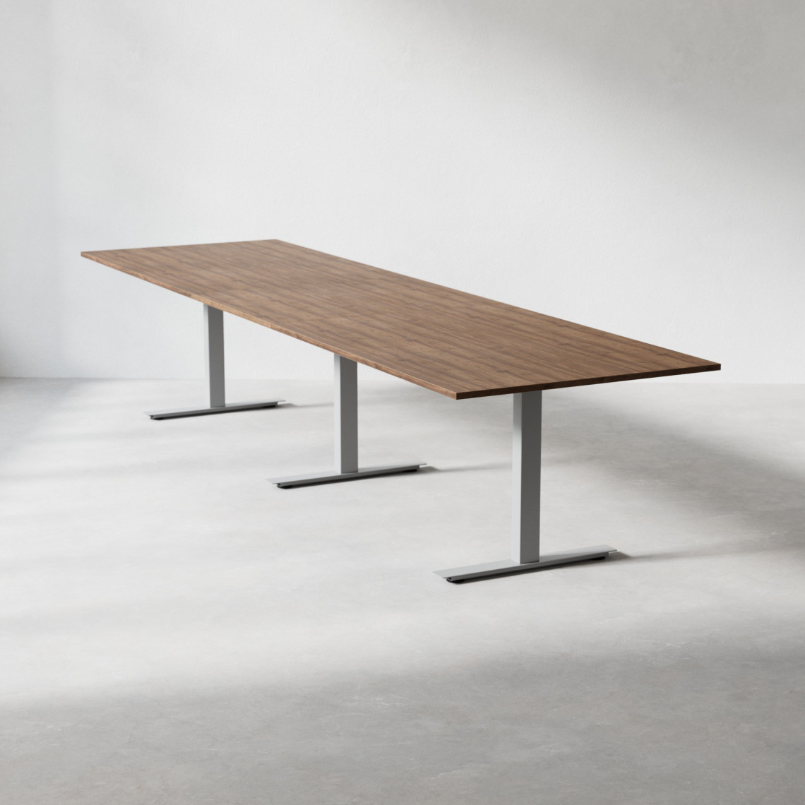 Konferensbord med valnötsfärgad laminatskiva 360x100 cm och silvrigt t-stativ.