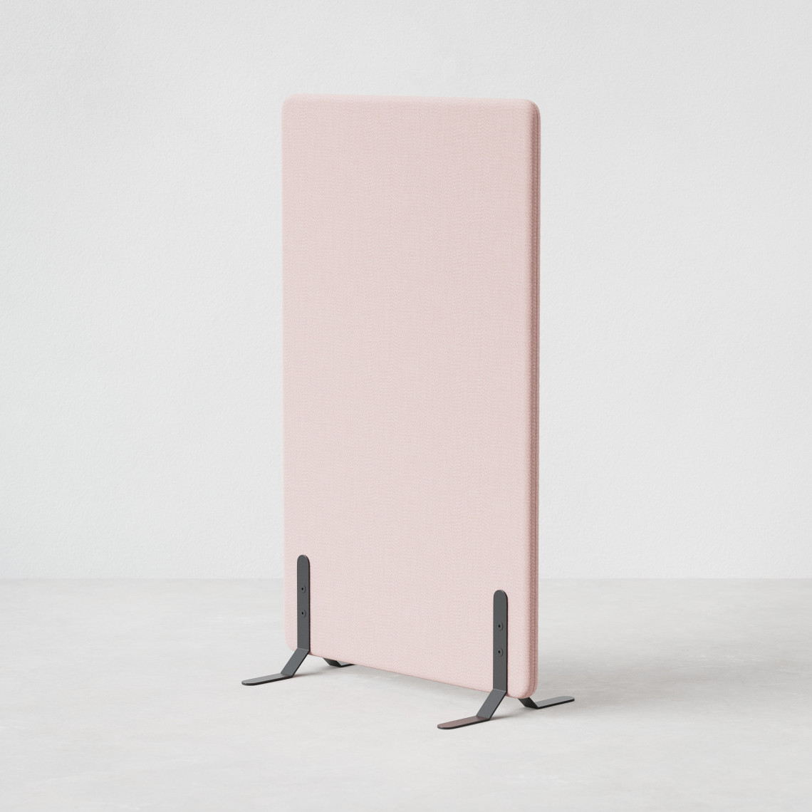 Ljudabsorberande golvskärm i rosa klädsel utrustad med svarta skärmfötter, snett från sidan.