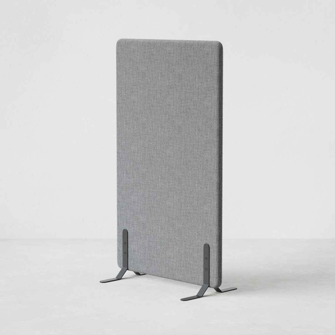 Ljudabsorberande golvskärm i grå klädsel utrustad med svarta skärmfötter, snett från sidan.