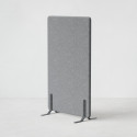 Ljudabsorberande golvskärm i grå klädsel utrustad med svarta skärmfötter, snett från sidan.