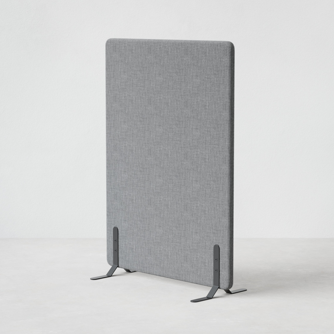 Ljudabsorberande golvskärm i grå klädsel utrustad med svarta skärmfötter, snett från sidan.
